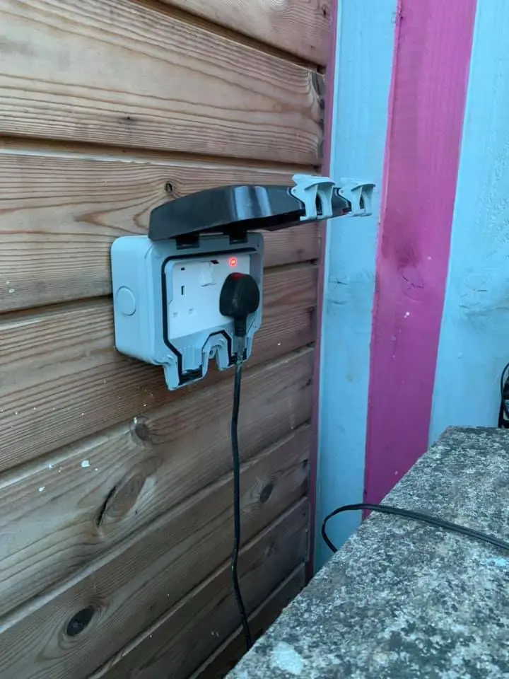 outdoor socket installation electrical services swansea - L & W Electrical Ltd Outdoor weatherproof electrical socket installed on a wooden wall by L&W Electrical Ltd, highlighting safe and efficient Electrical Serivces in Swansea.
